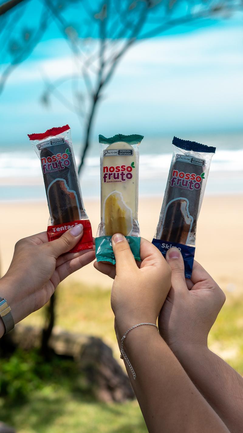 Grupo de amigos com picolés Nosso Fruto na praia